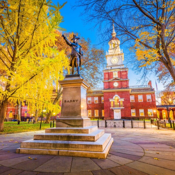 Bronze statue on a tall pedestal with Independence Hall in the background.