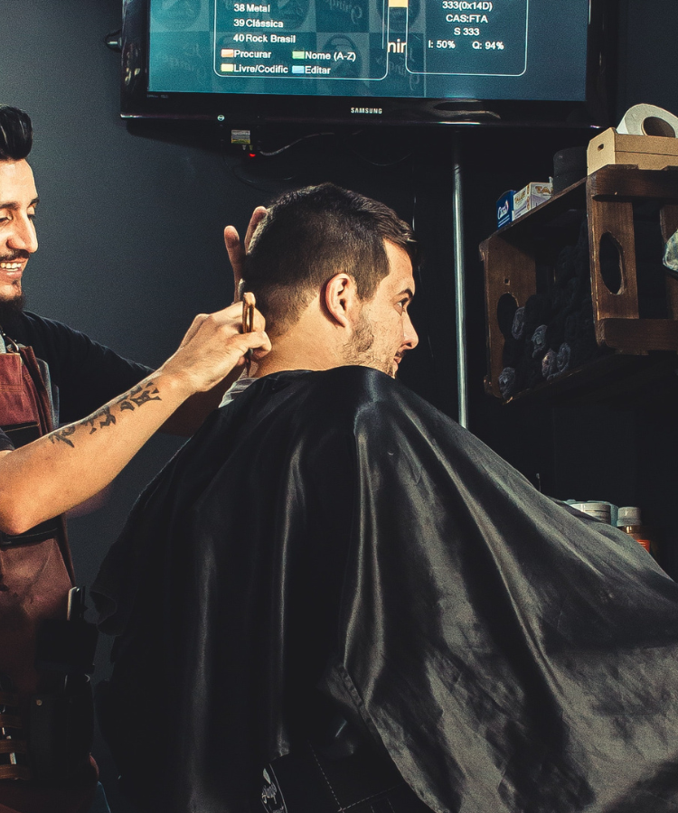 Peluquero cortando el pelo a un joven en una barbería.