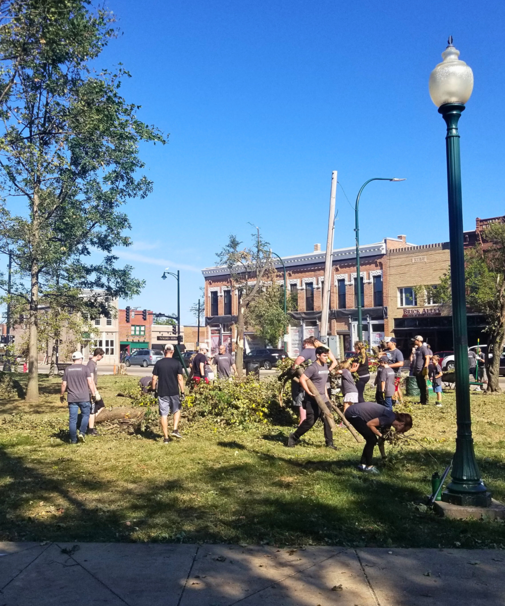 Volunteers in a downtown park cleaning up fallen tree limbs and other debris