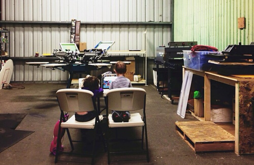 Two young boys sit on folding chairs in office