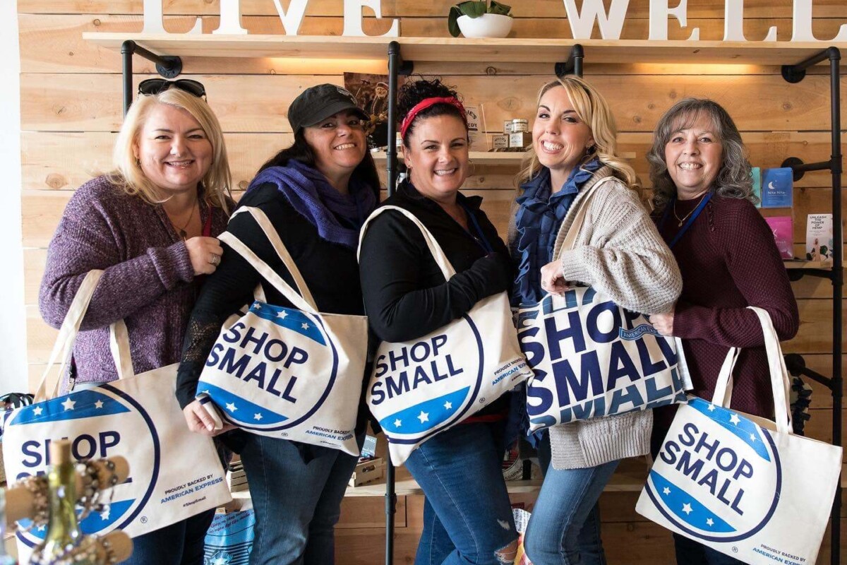 Un grupo de mujeres posa con un grupo de bolsas "Shop Small".