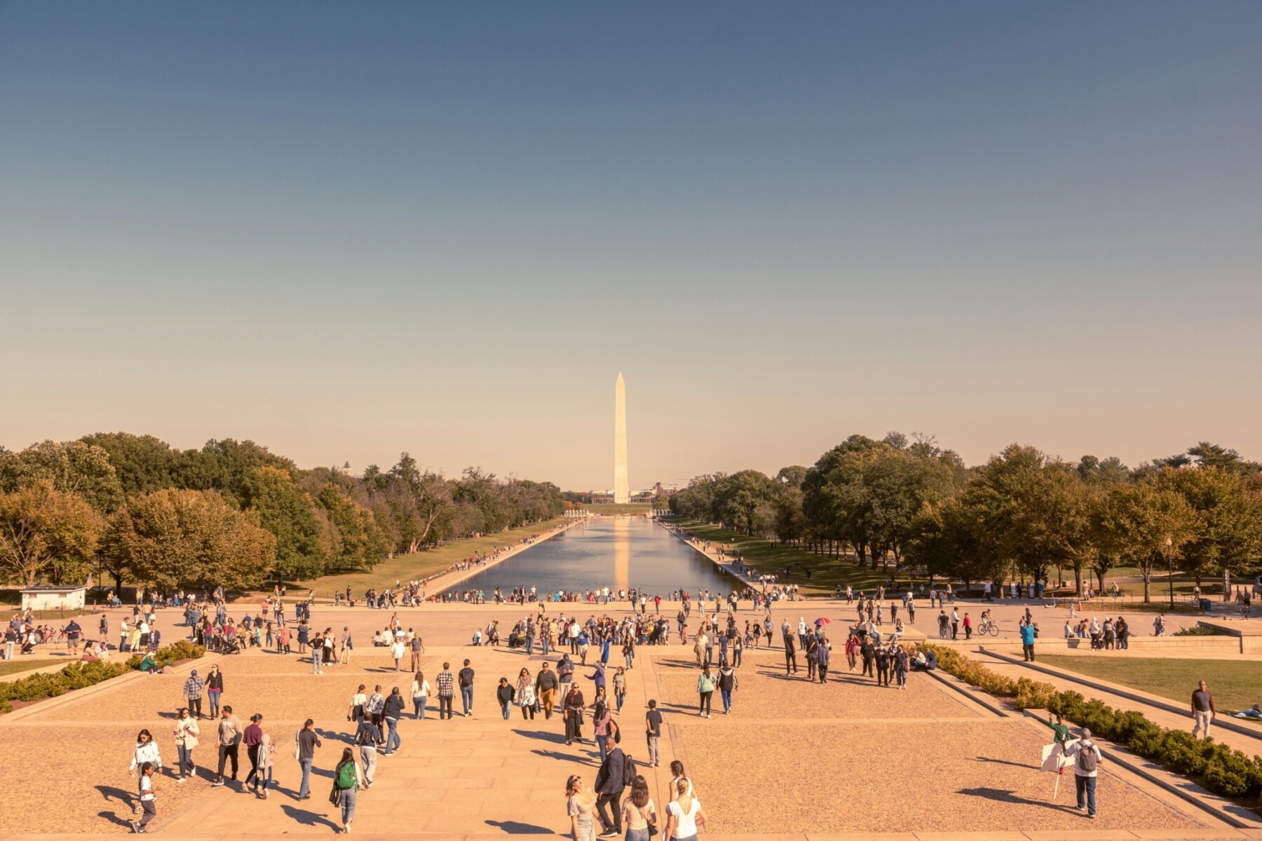 People walking on the national mall with the Washington monument in the background