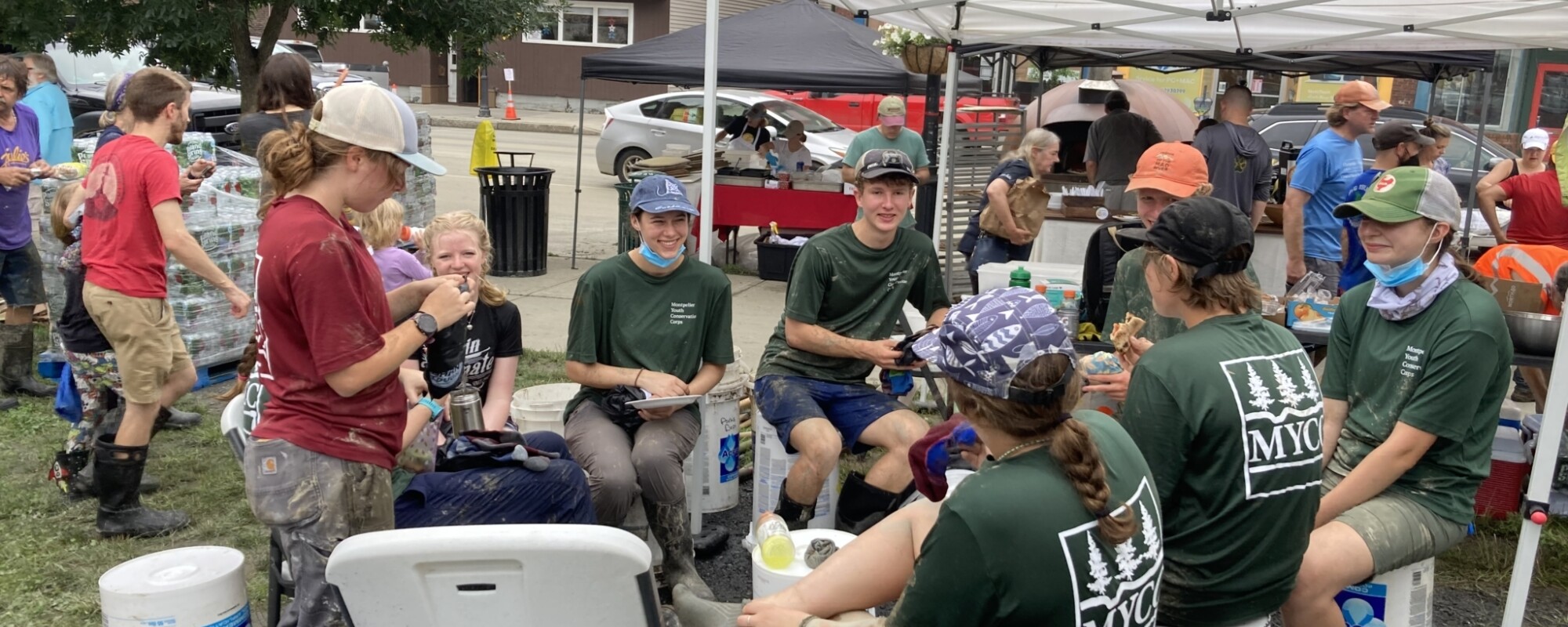 A group of volunteers sit on buckets and chairs taking a break during flood cleanup