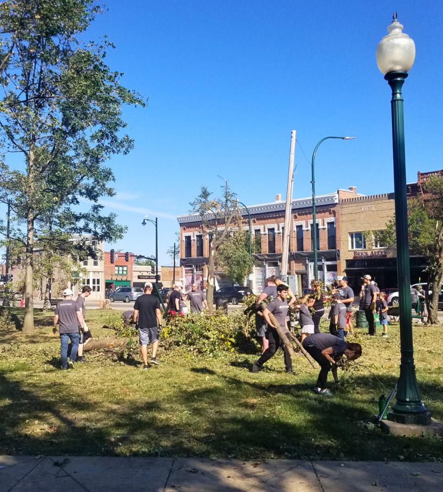 Volunteers in a downtown park cleaning up fallen tree limbs and other debris