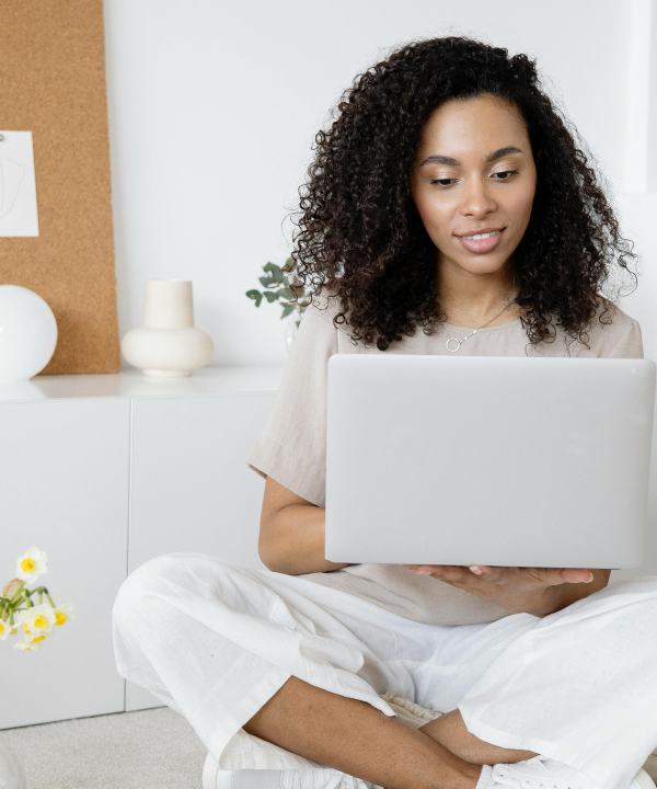 Woman sitting cross-legged on desk looking at laptop.