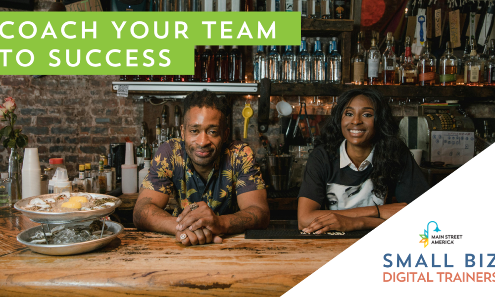 Man and woman lean on wooden bar top next to plate of food in front of bar shelving on an exposed brick wall. In front of photo, text reads, "Coach your team to success." In bottom right-hand corner, text reads, "Small Biz Digital Trainers" below Main Street America logo.