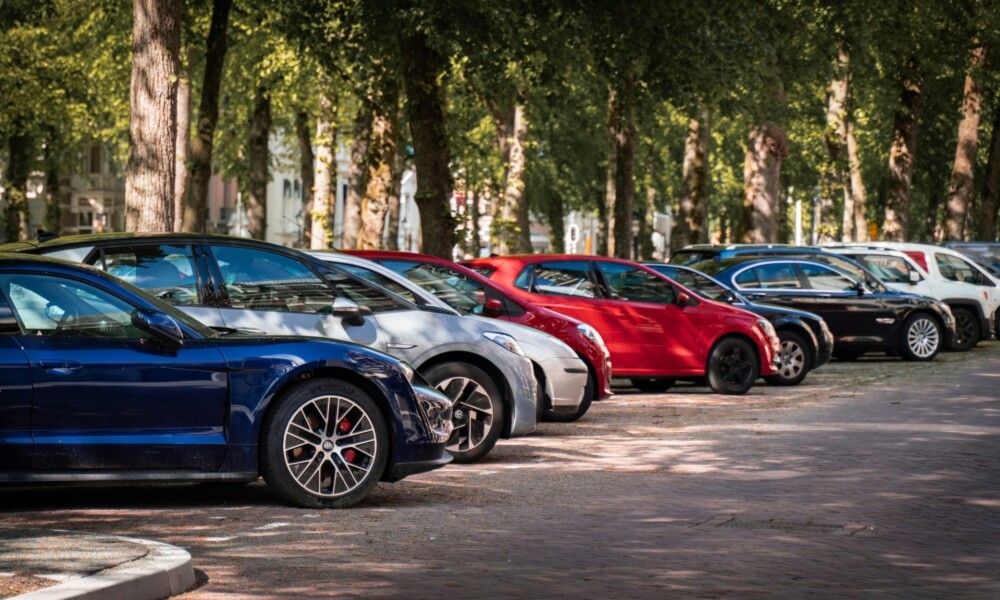 A row of cars parked on a shaded, tree-lined street