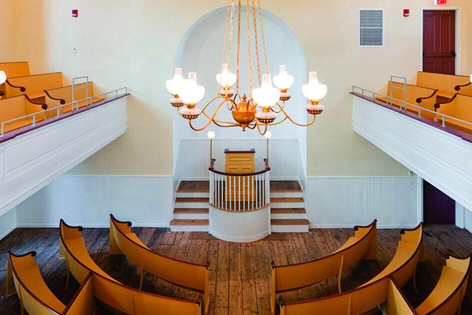 View from the balcony of the African American Meeting House in Boston, Massachusetts showing wood pews facing a front podium.