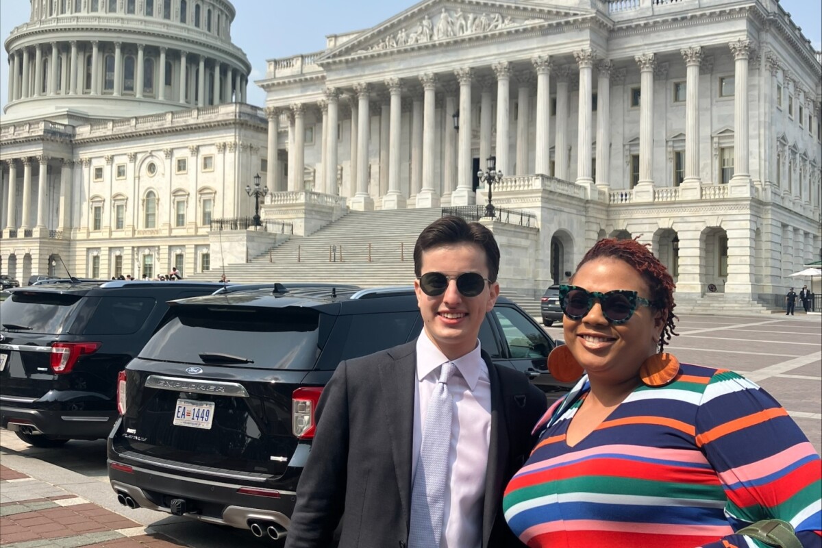 Two people pose in front of the US Capitol building