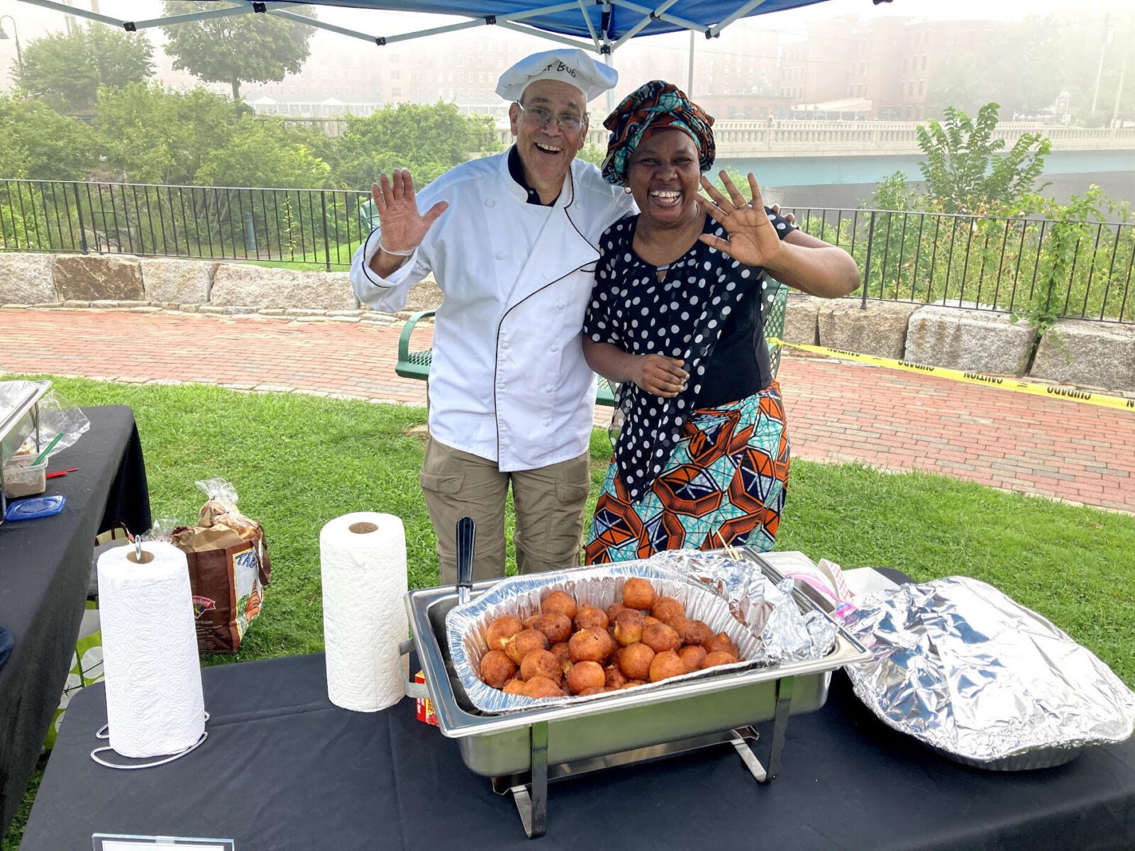 Two vendors pose at the Cultural Cuisines tent during the River Jam event in Biddeford, Maine