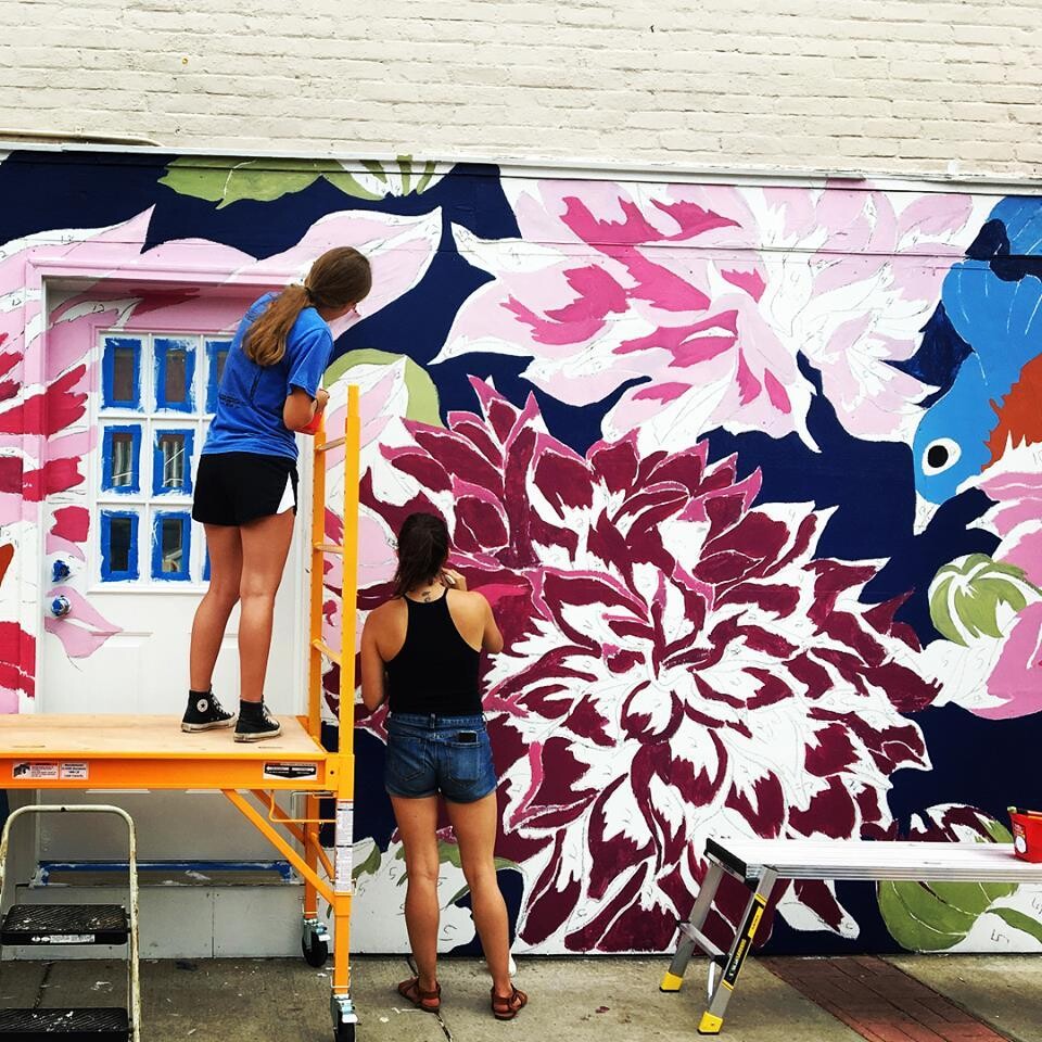 Two people working on a large mural