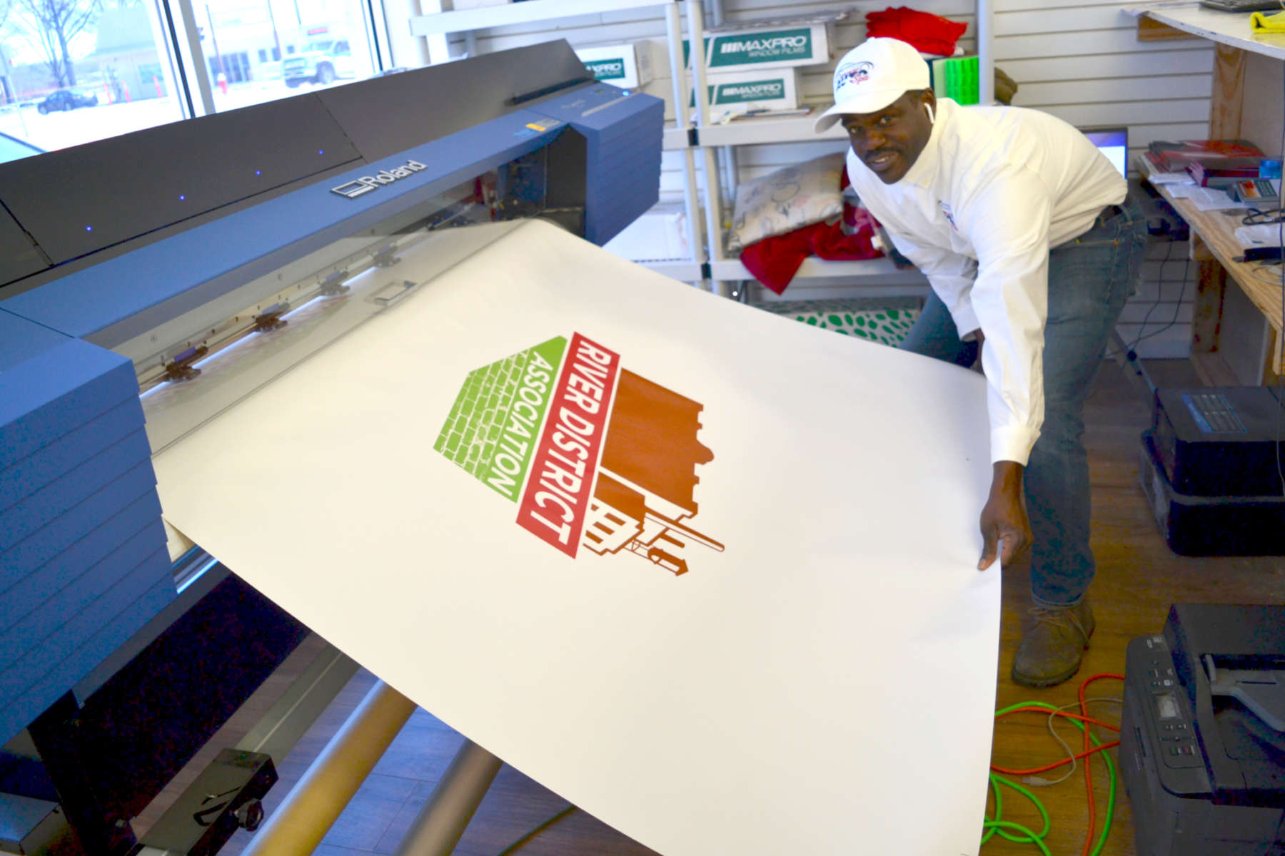 A man pulls a large piece of paper out of a printer