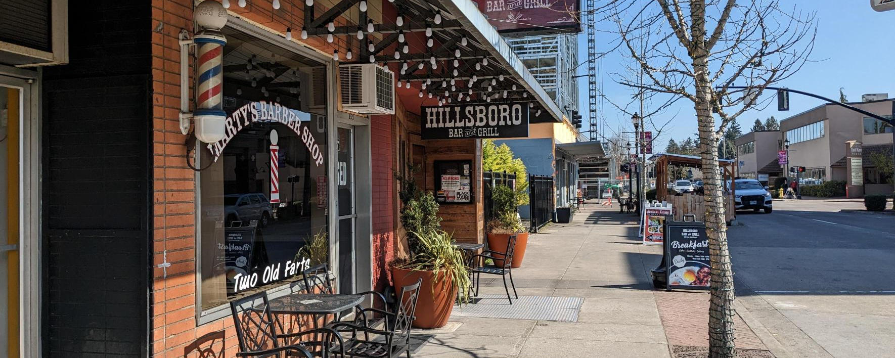 Vibrant storefronts and outdoor seating line a downtown street.