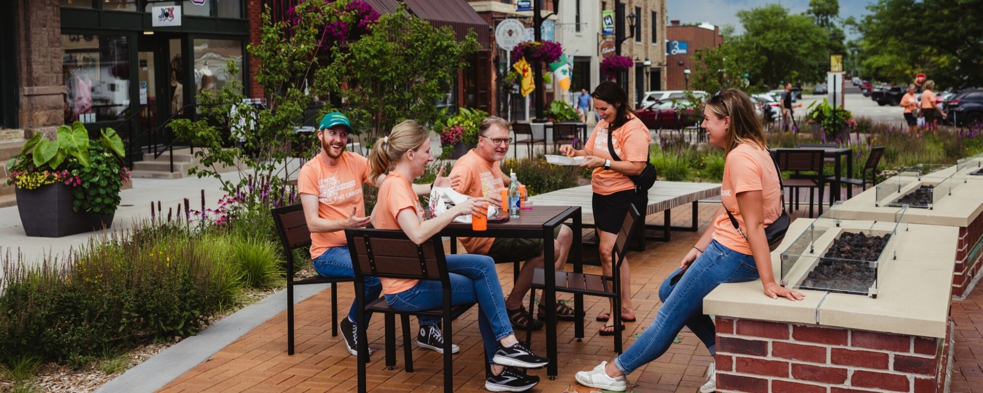 People wearing branded Uptown Marion shirts gather around a table in downtown Marion, Iowa