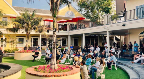 People gather in a grassy outdoor plaza for a community engagement meeting