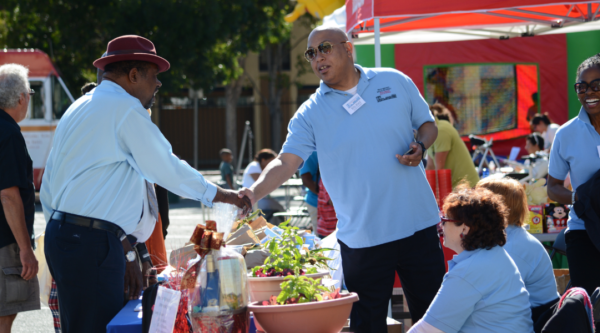 Two African American men shake hands at an outdoor market