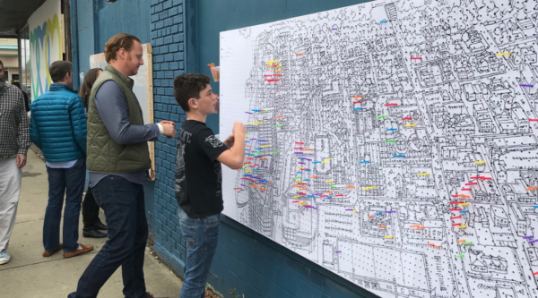 People add colored pins to a map of downtown during a community planning exercise