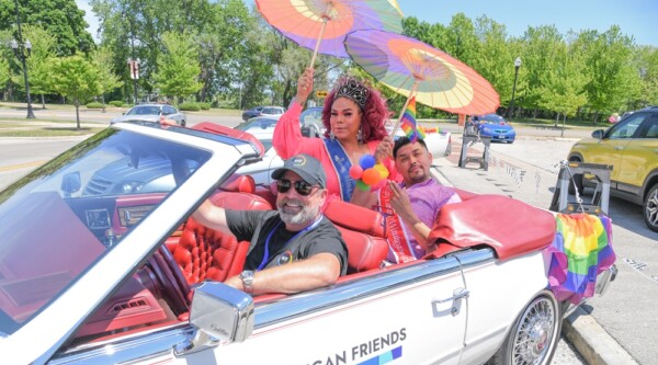 Waukegan pride event, people wearing rainbow attire riding in a car during a parade