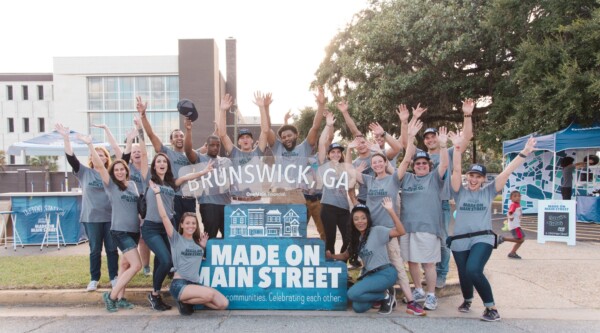 People pose behind a sign for the Brunswick, GA Made on Main Street event