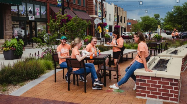 People wearing branded Uptown Marion shirts gather around a table in downtown Marion, Iowa
