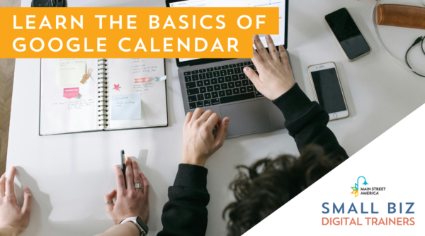 Desde arriba, las manos de dos personas sobre un escritorio frente a un ordenador, un portátil y teléfonos, mirando calendarios. Sobre la foto, texto: "Aprende los conceptos básicos de Google Calendar". En la esquina inferior derecha, texto: "Small Biz Digital Trainers" con el logotipo de Main Street America.