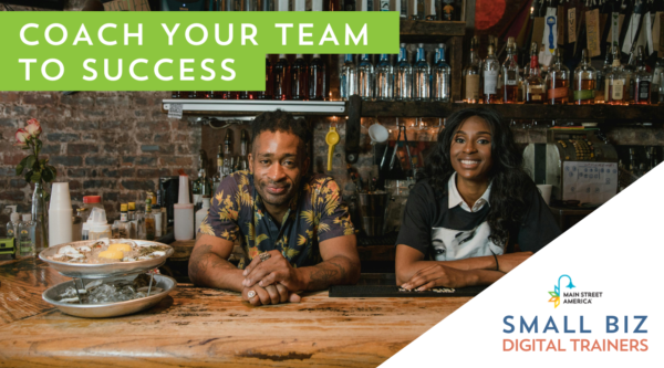 Man and woman lean on wooden bar top next to plate of food in front of bar shelving on an exposed brick wall. In front of photo, text reads, "Coach your team to success." In bottom right-hand corner, text reads, "Small Biz Digital Trainers" below Main Street America logo.