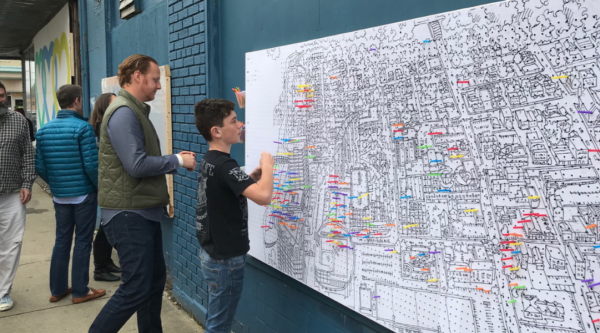 People participating in a downtown mapping exercise by putting pins in a large map