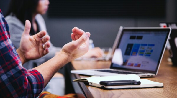 People sitting at a table with laptops having a meeting