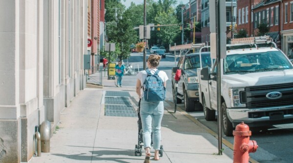 A woman pushing a stroller down a sidewalk