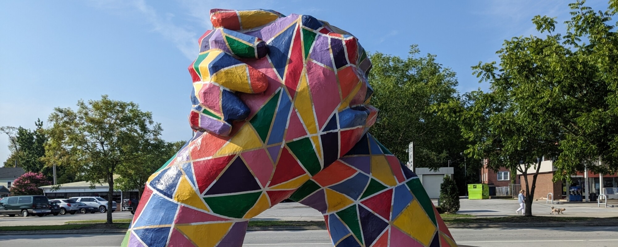 Large, multi-colored sculpture of hands rising up from the ground and clasping.