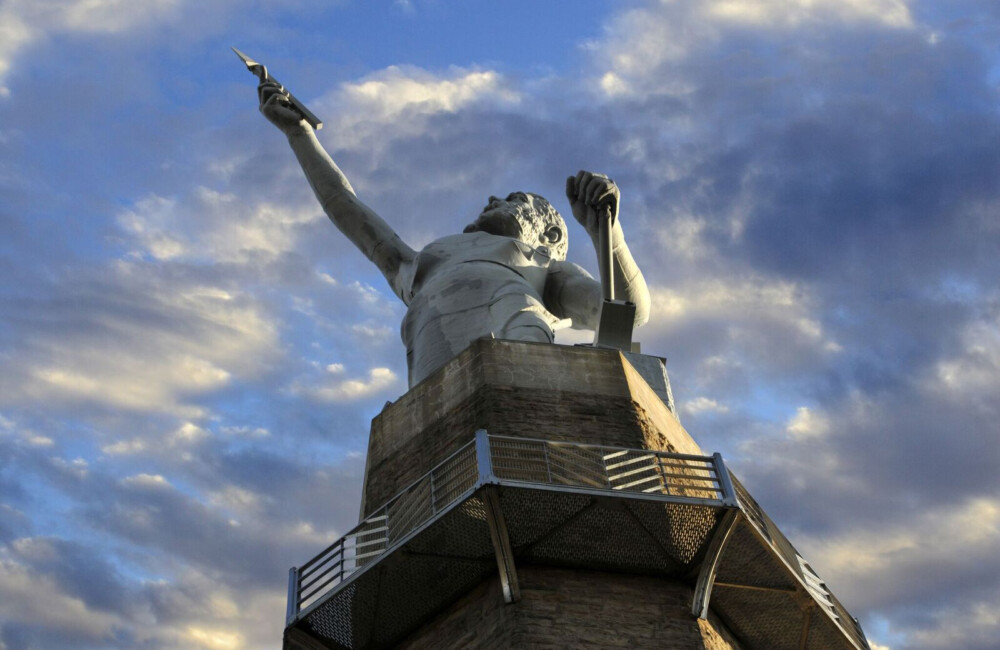 Upshot view of a large statue with its right hand outstretched towards the sky.