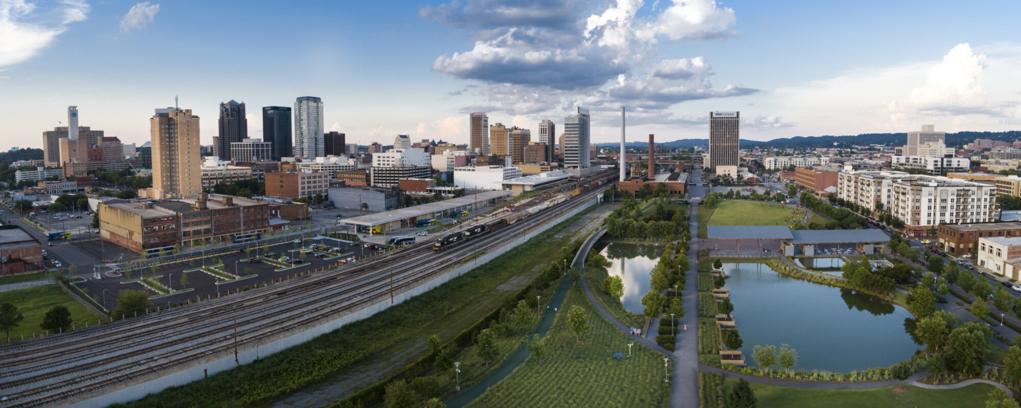 Aerial of a city skyline (left) and large park (right) divided by railroad tracks.