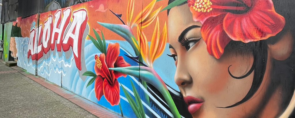 A mural showing a Native Hawaiian woman with a red flower in her hair alongside other flowers and the word "Aloha"