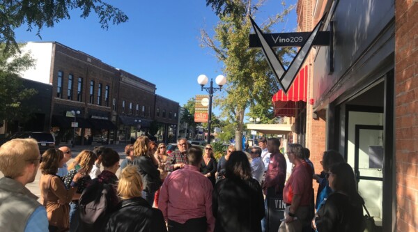 Group of people gather for tour outside of historic building in a downtown area.