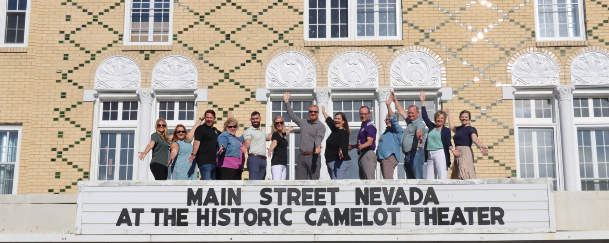 A group of people strike poses while standing atop a historic theater marquee.