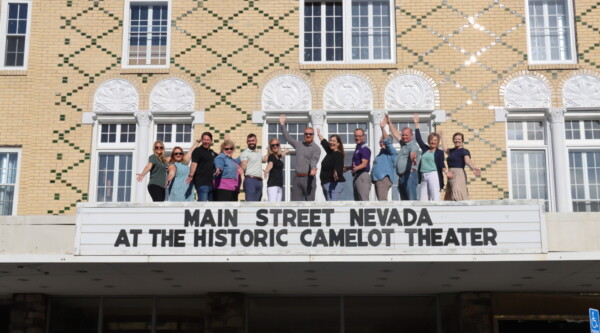 A group of people strike poses while standing atop a historic theater marquee.