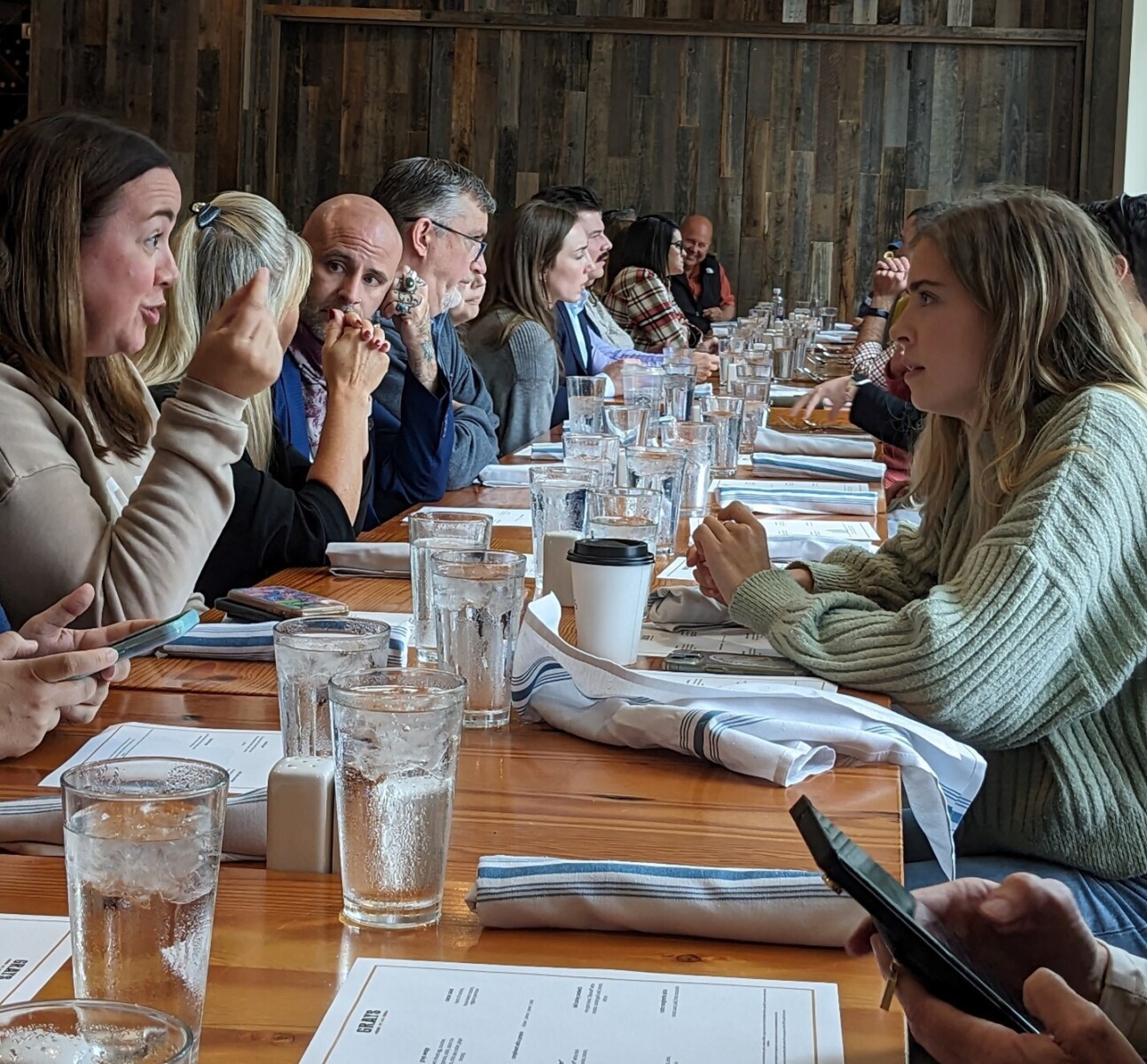 People sit on either side of a long dinner table