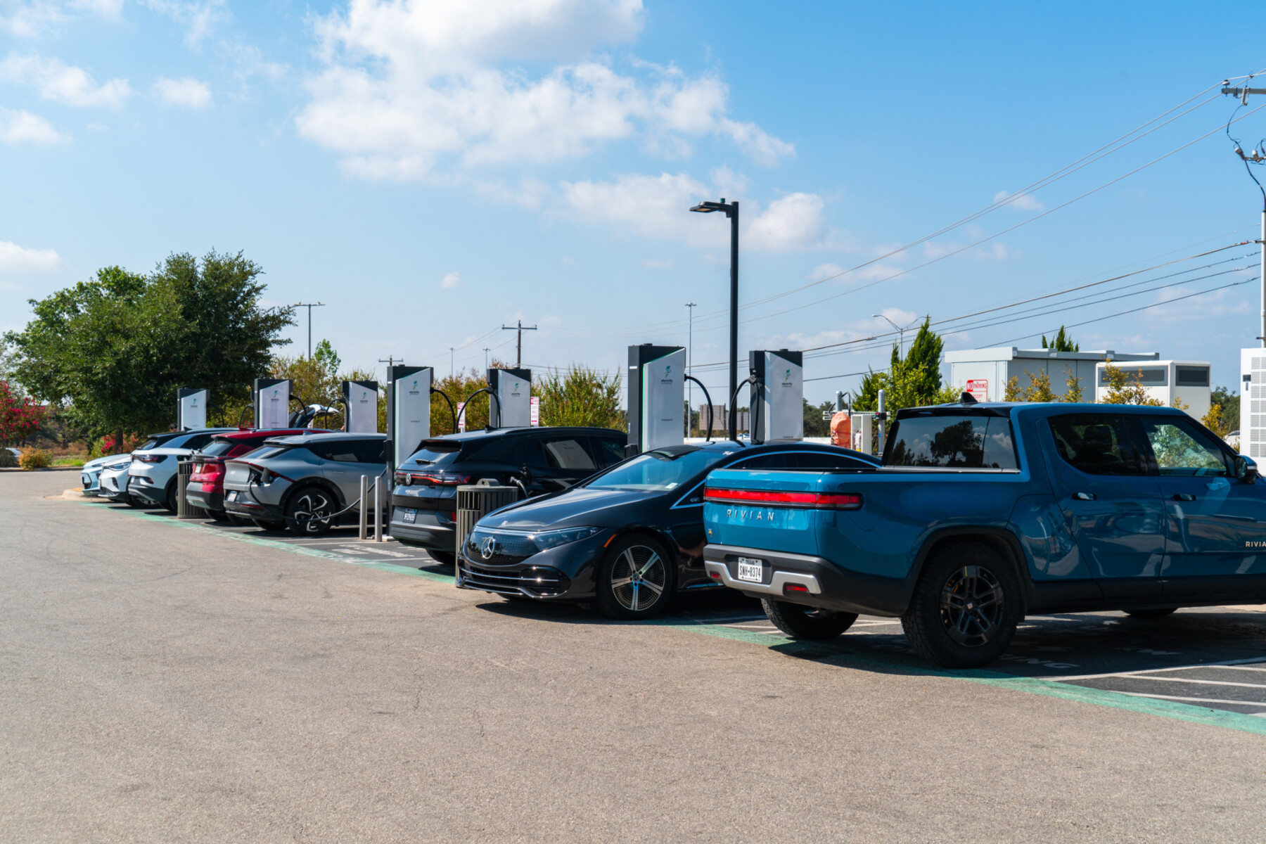 A row of vehicles using electric vehicle chargers in a parking lot