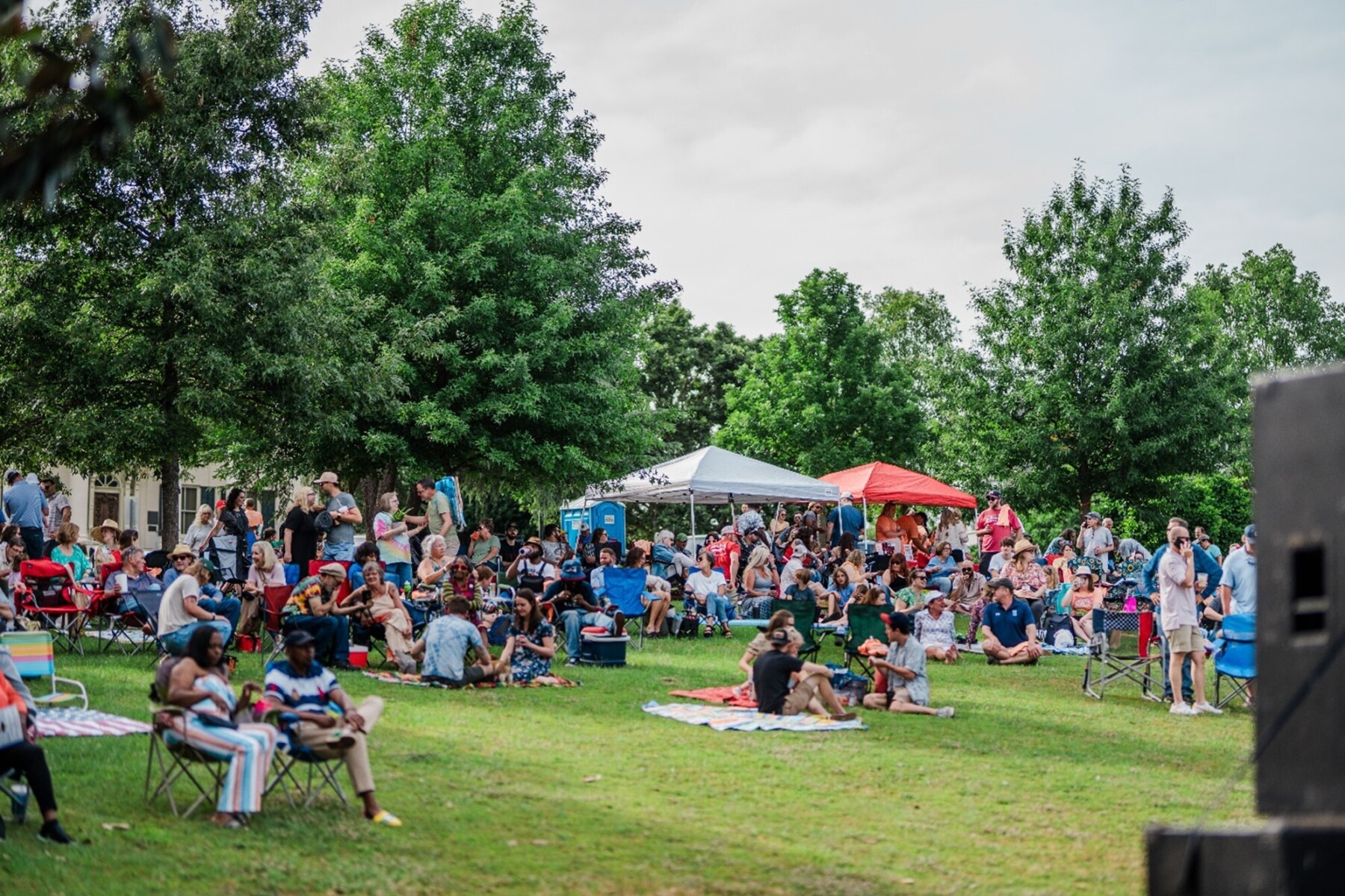 People sitting on chairs and picnic blankets at an outdoor concert