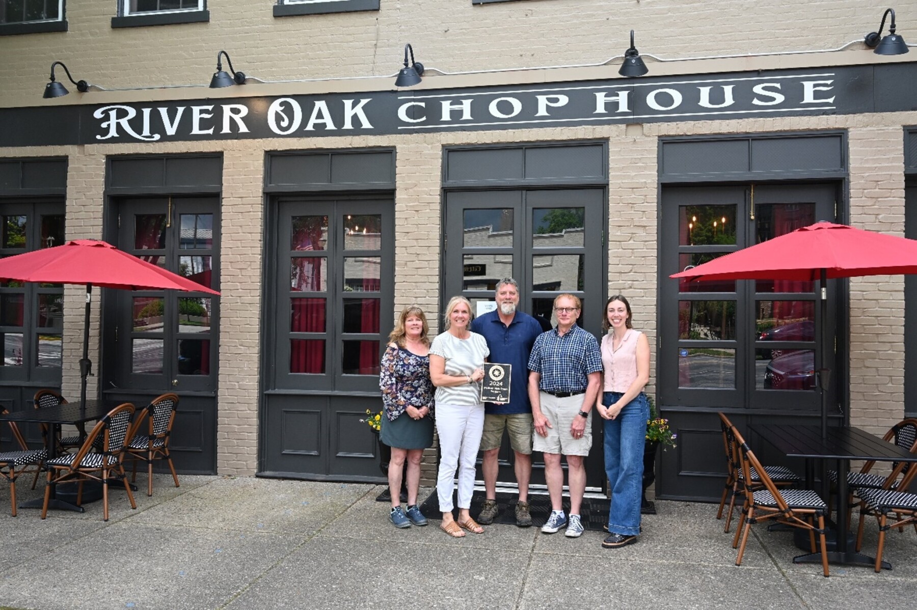 A group of people pose in front of a downtown restaurant holding the GAMSA plaque