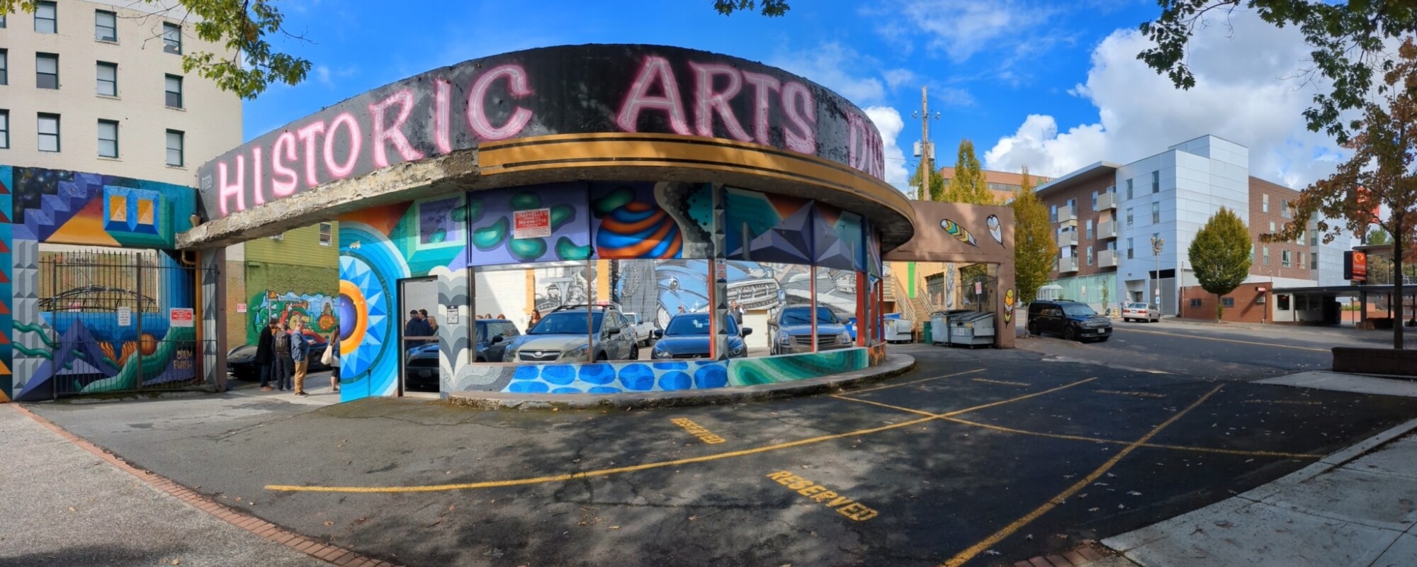 A downtown building with a curved facade featuring a mural with the words "historic arts"