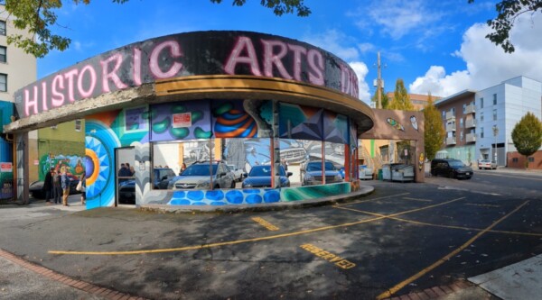 A downtown building with a curved facade featuring a mural with the words "historic arts"