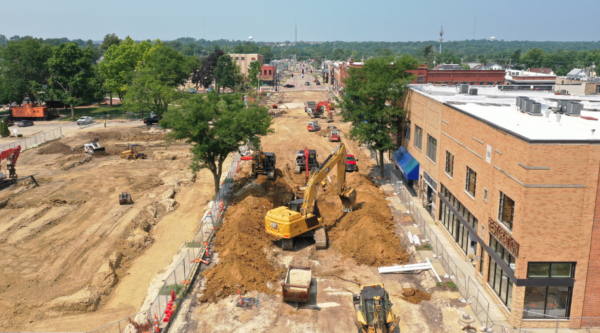 An excavator digs up dirt to create a new streetscape in a historic downtown