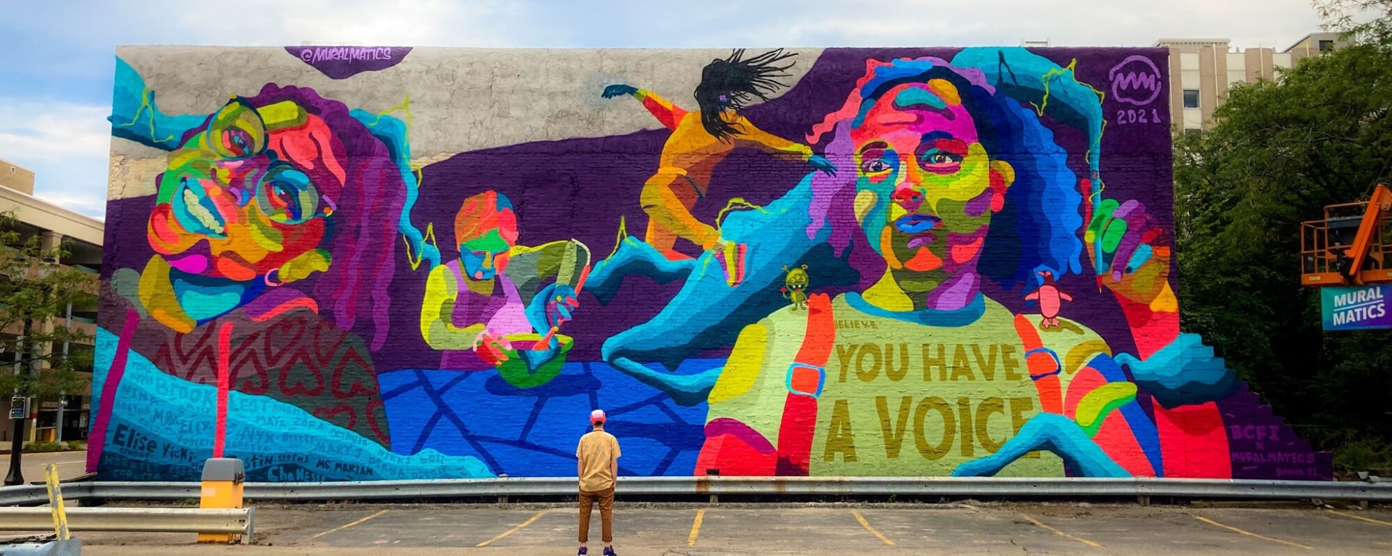 A large colorful mural featuring the faces of children and the words "you have a voice"