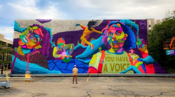 A large colorful mural featuring the faces of children and the words "you have a voice"