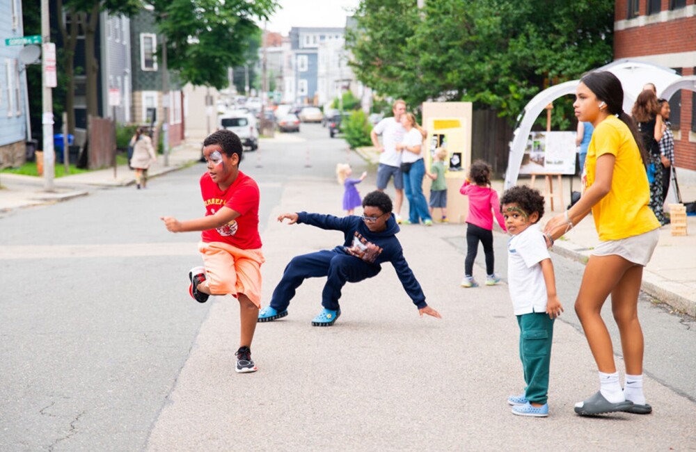 A group of children dance in the street during an outdoor event