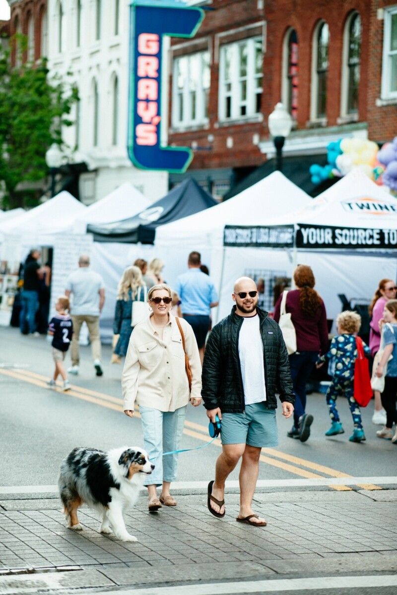 A couple and a dog stroll through a downtown market event