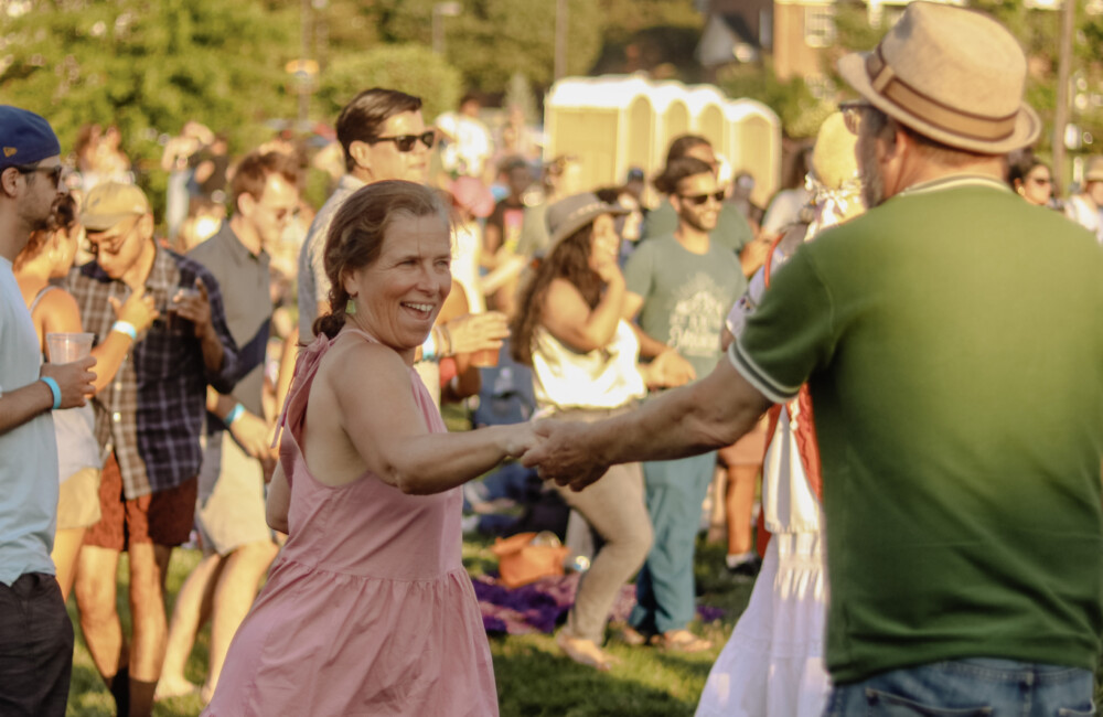 Man and woman dance to live music at outdoor venue.