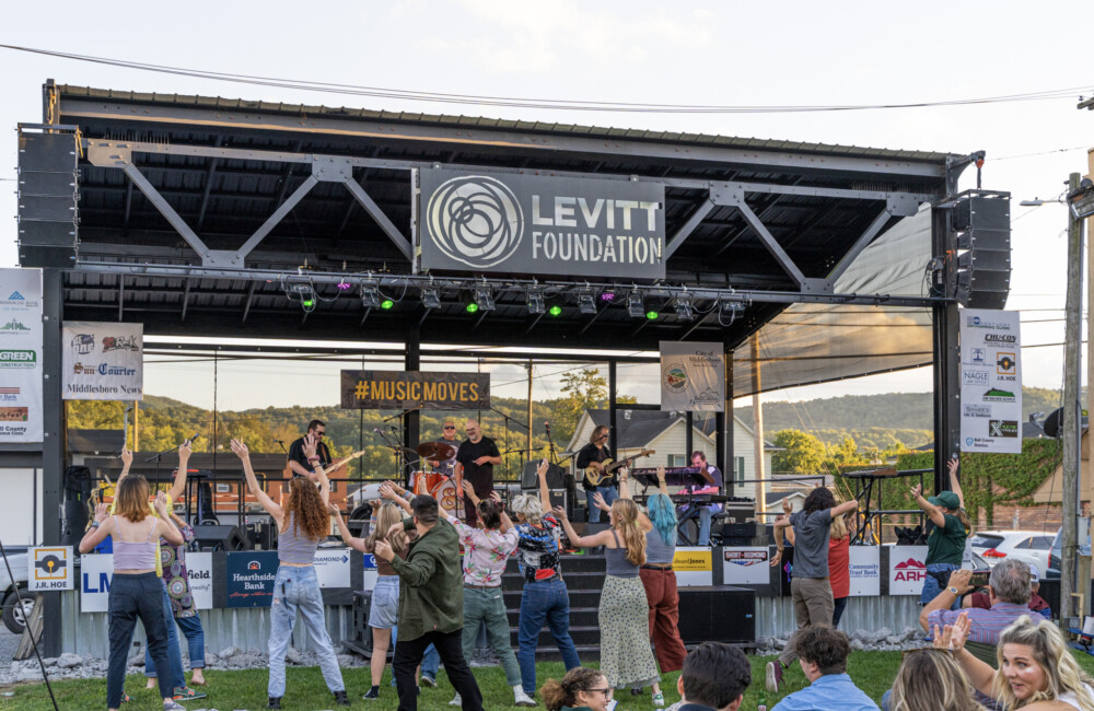 Group of people dance in front of outdoor stage