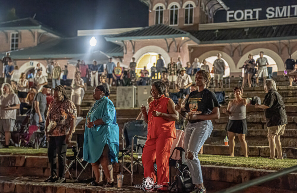 People dancing in outdoor seating at night.